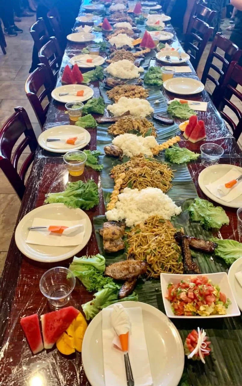 A boodle fight: a long table covered in banana leaves, rice and dishes